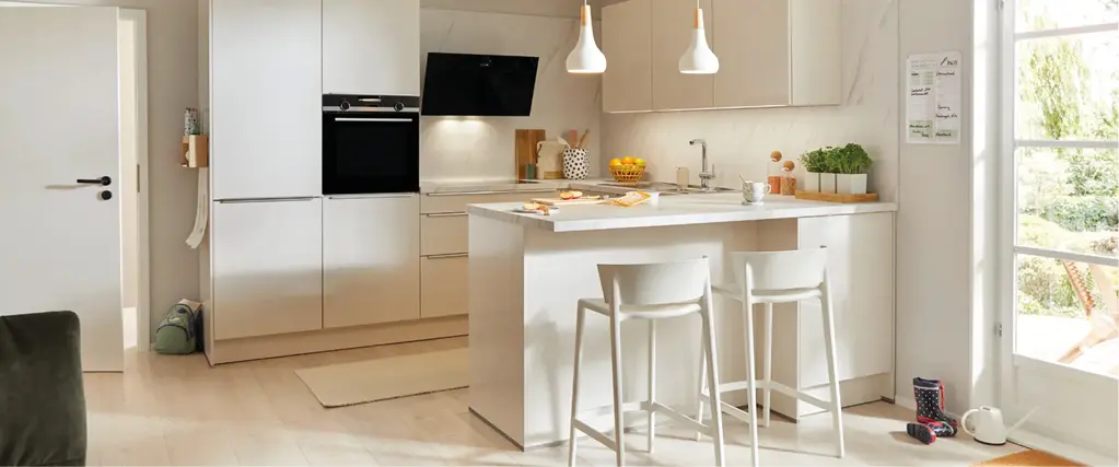 Moderne Küche mit weißer Kochinsel, Barhockern und klaren Linien. Hochwertige Küchenmöbel verbinden Funktionalität und Design für zeitgemäßes Kochen und Wohnen.
